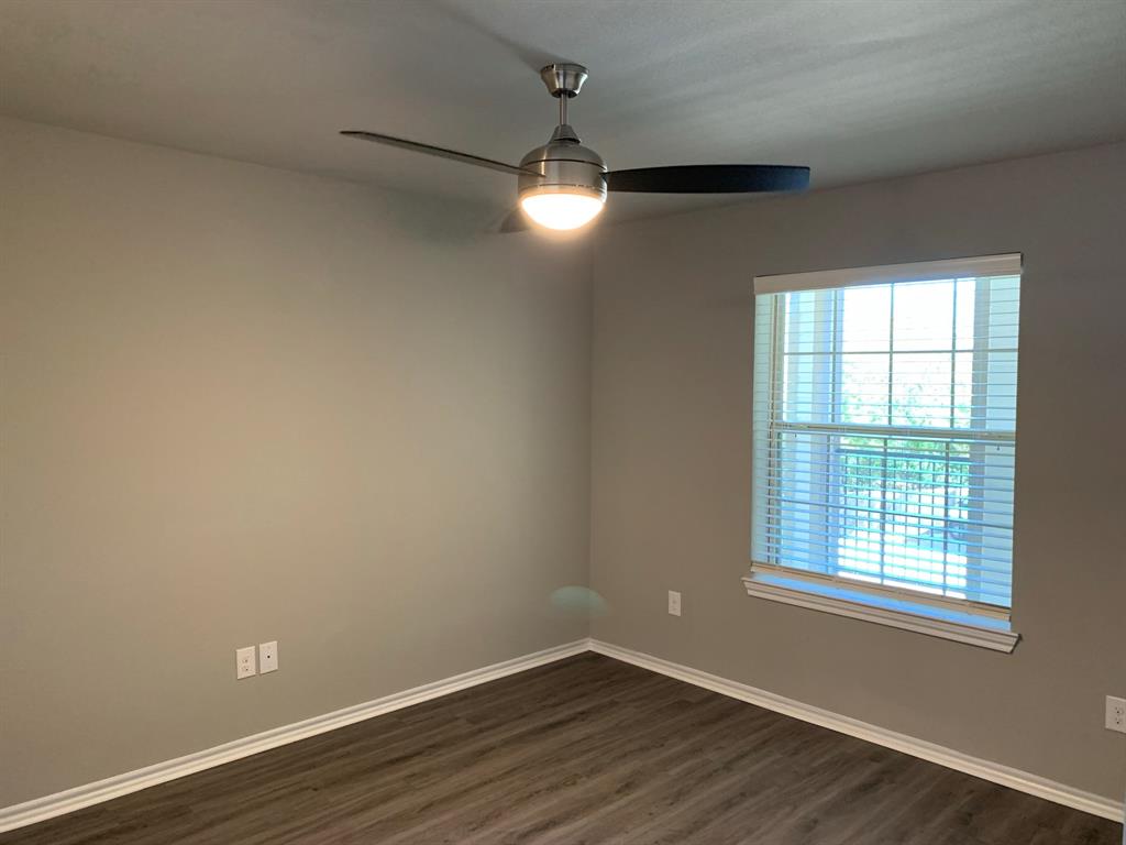 6108 Abrams Road, Unit 514 Dallas, TX 75231 - Photo 6 of 9 an empty room with wooden floor and windows
