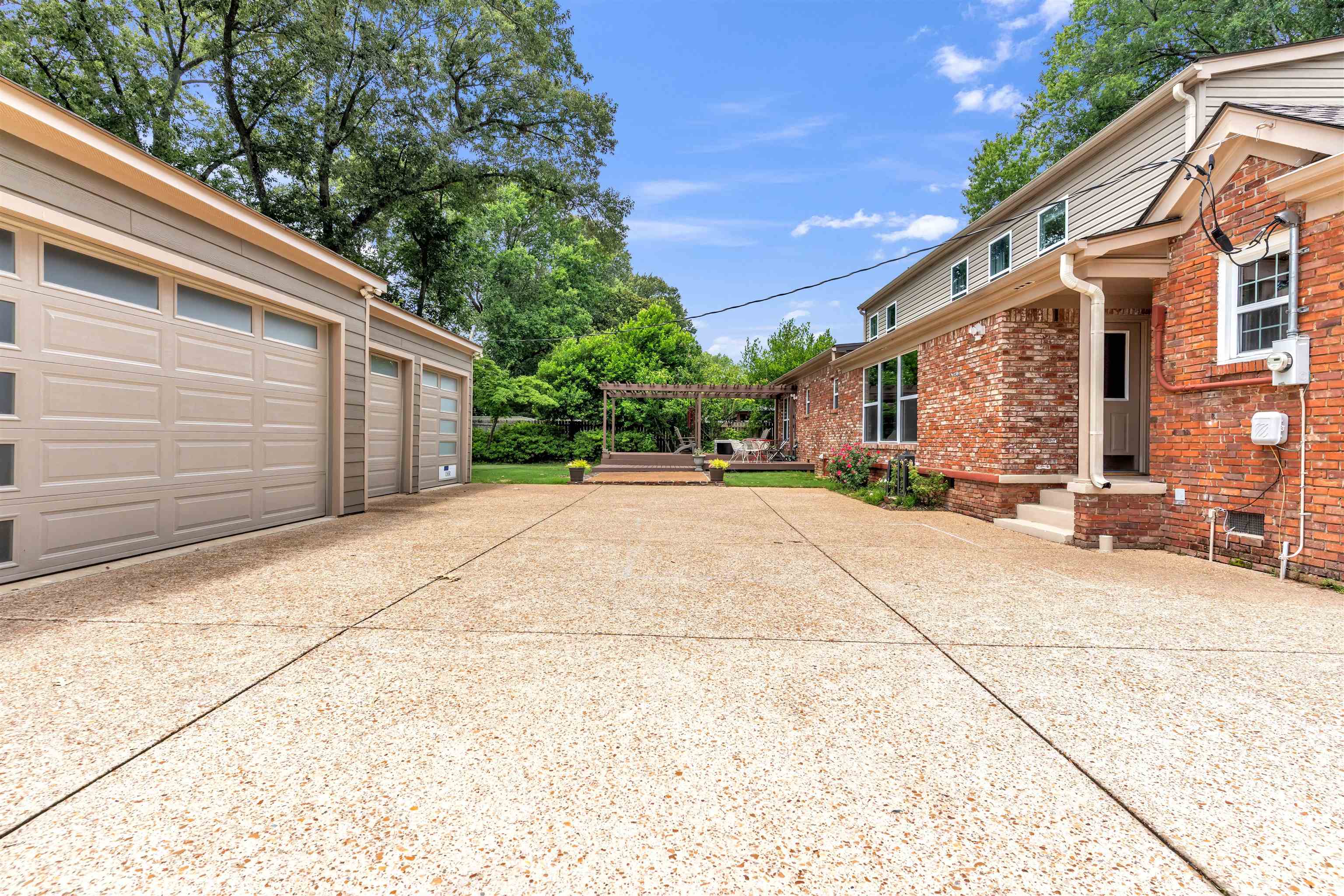 5187 South Angela Road Memphis, TN 38117 - Photo 33 of 39 Expansive exposed aggregate driveway with a three-car garage featuring frosted glass panels