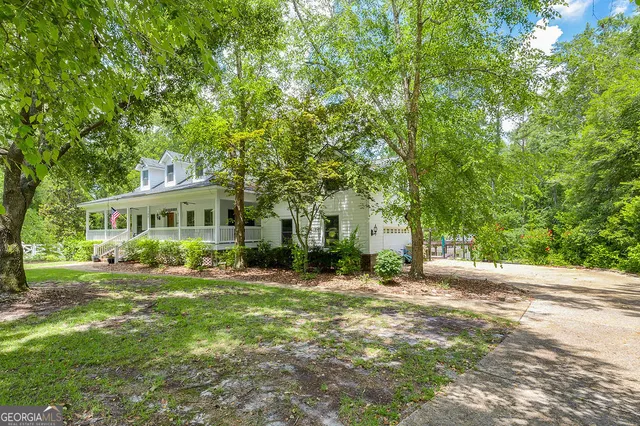 a view of a house with a big yard and large trees