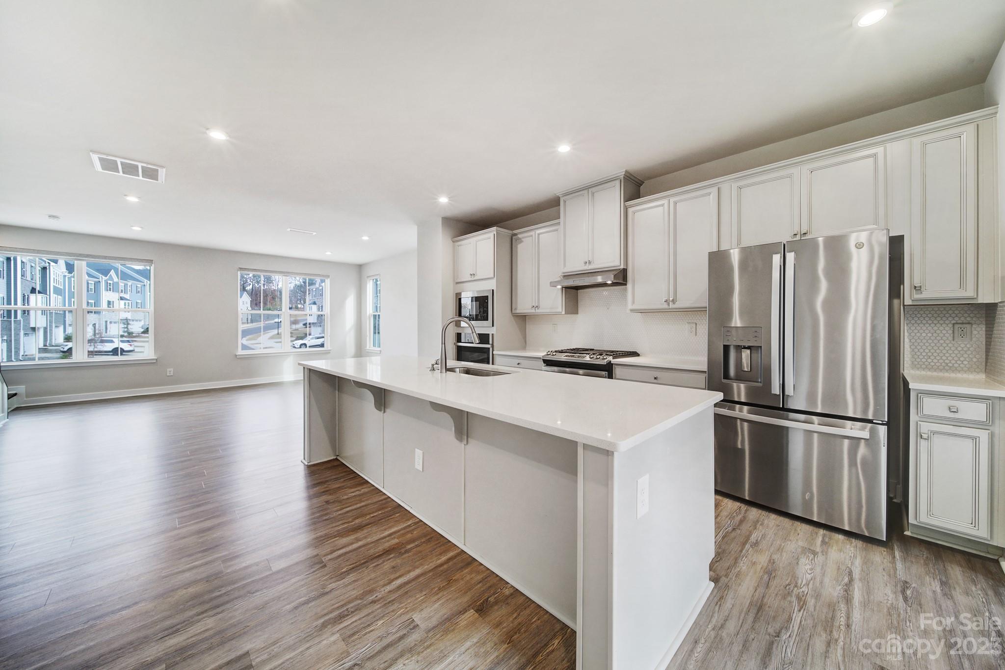 622 Crudent Road Tega Cay, SC 29708 - Photo 15 of 40 a kitchen with stainless steel appliances a refrigerator a sink dishwasher a stove and white cabinets with wooden floor