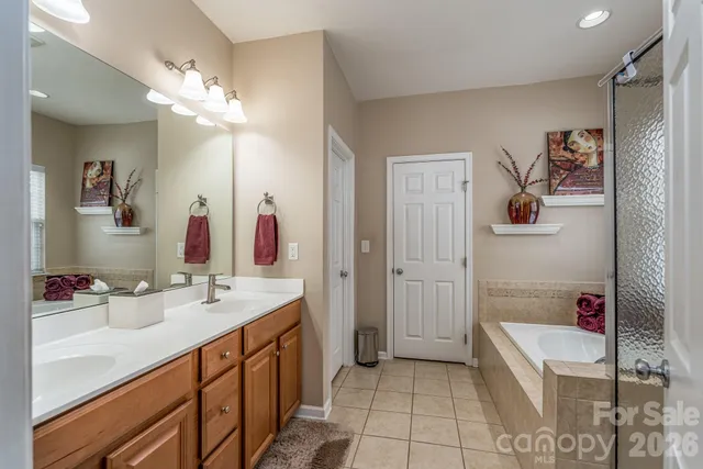 a spacious bathroom with a double vanity sink a mirror a bathtub and shower