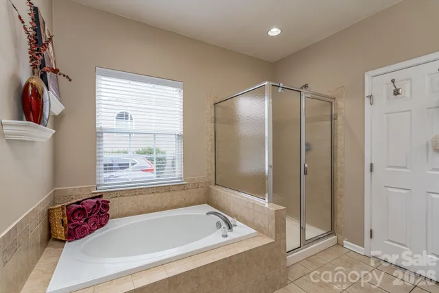 a bathroom with a tub a shower and a window