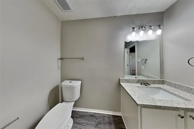 a bathroom with a granite countertop sink a toilet and a mirror
