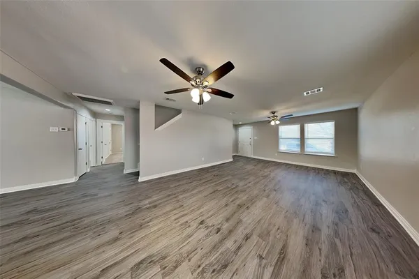 an empty room with wooden floor and ceiling fan