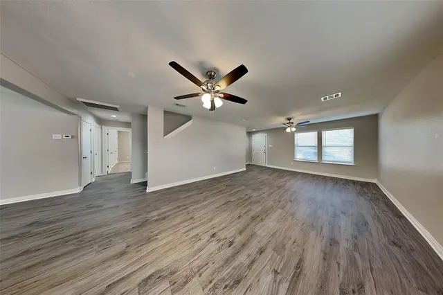 an empty room with wooden floor and ceiling fan