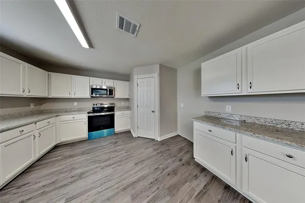 a kitchen with granite countertop white cabinets and white appliances