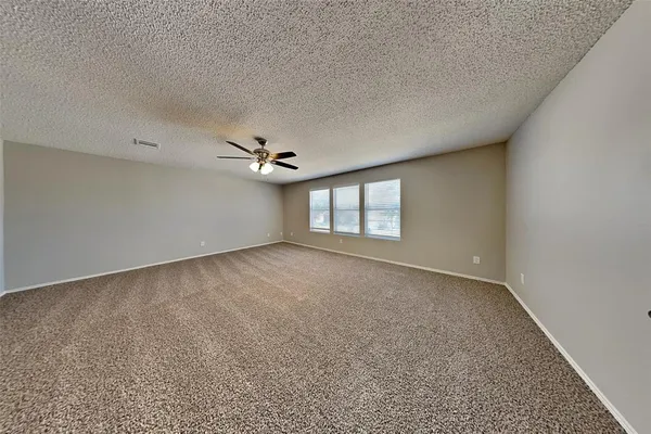 an empty room with windows and ceiling fan
