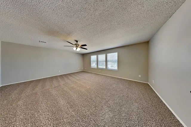 an empty room with windows and ceiling fan