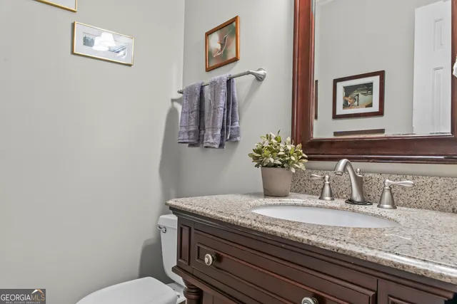 a bathroom with a granite countertop sink a toilet and mirror