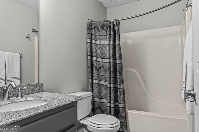 a bathroom with a granite countertop sink toilet and shower