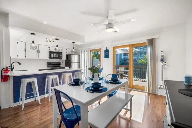 a kitchen with stainless steel appliances granite countertop a stove a refrigerator a kitchen island a dining table and chairs with wooden floor