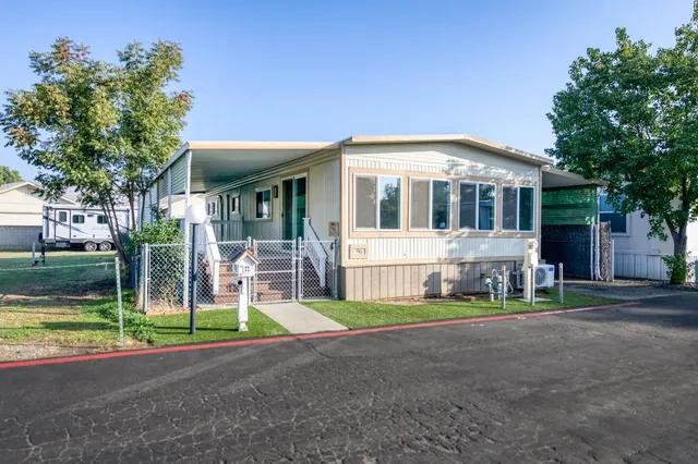 a front view of a house with a garden and trees