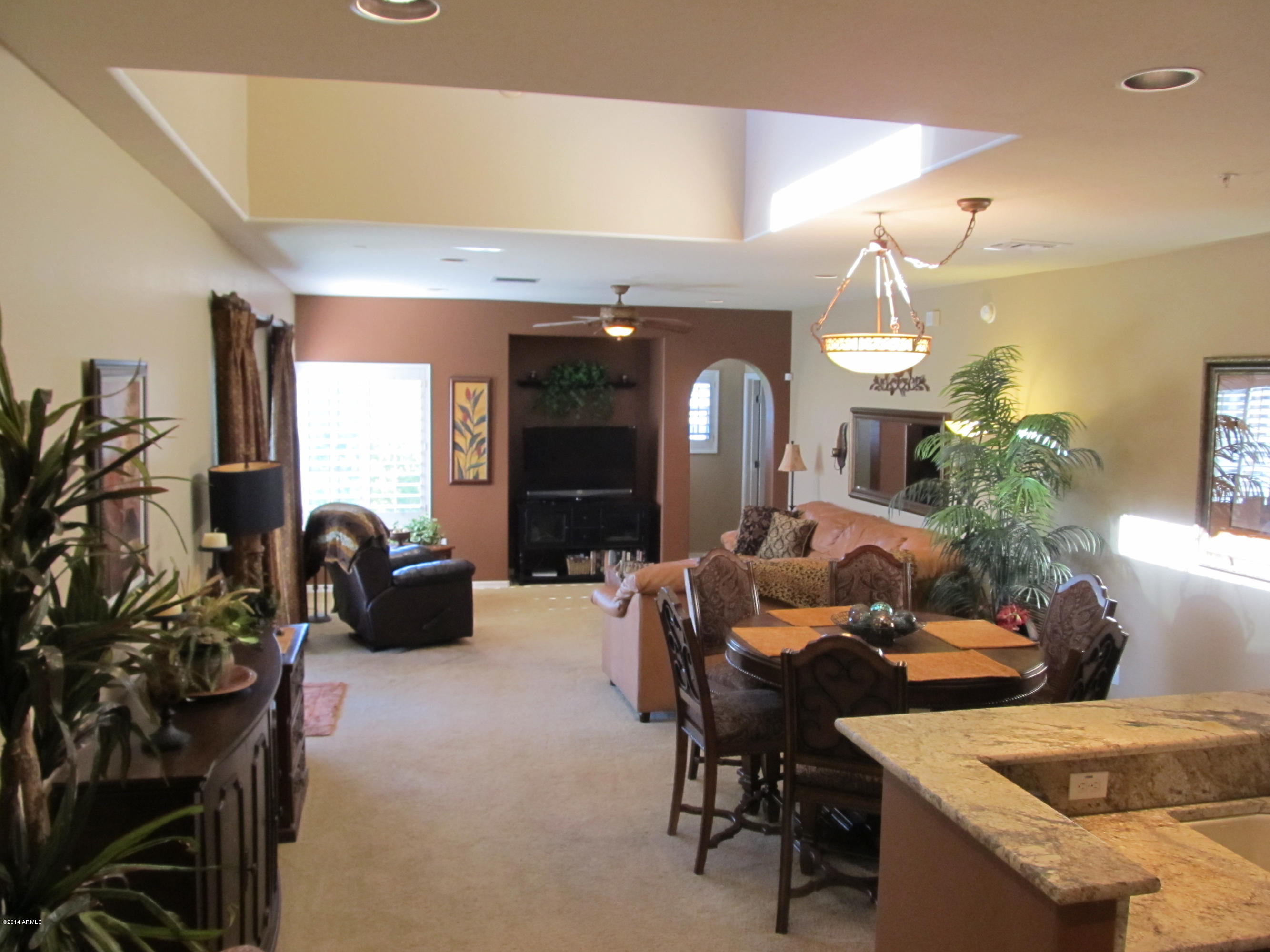 3935 East Rough Rider Road, Unit 1358 Phoenix, AZ 85050 - Photo 2 of 15 a living room with furniture a chandelier and a potted plant