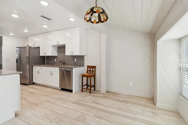 a kitchen with a sink stainless steel appliances cabinets and a window