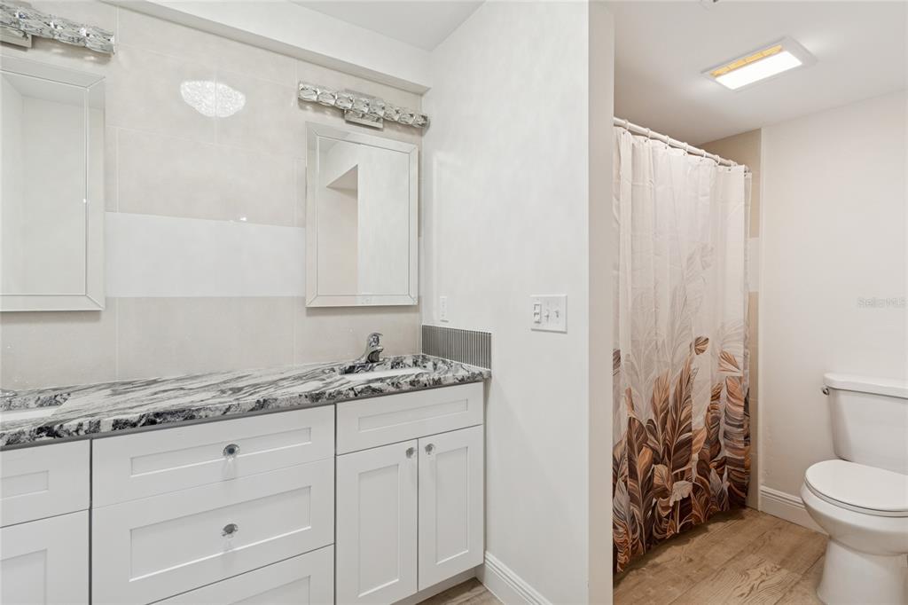 9628 Davis Road Tampa, FL 33637 - Photo 15 of 44 a bathroom with a granite countertop sink a toilet and a mirror