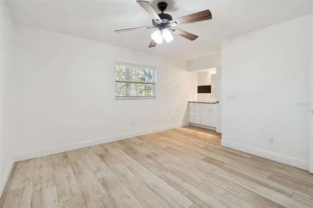 an empty room with wooden floor fan and windows