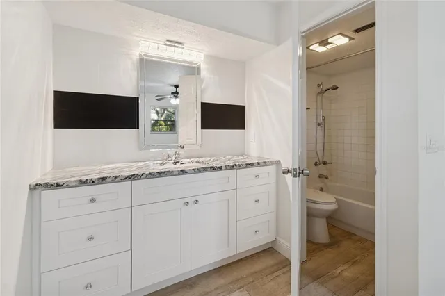 a bathroom with a granite countertop sink toilet and mirror