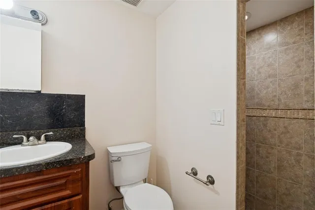 a bathroom with a granite countertop sink toilet and a mirror