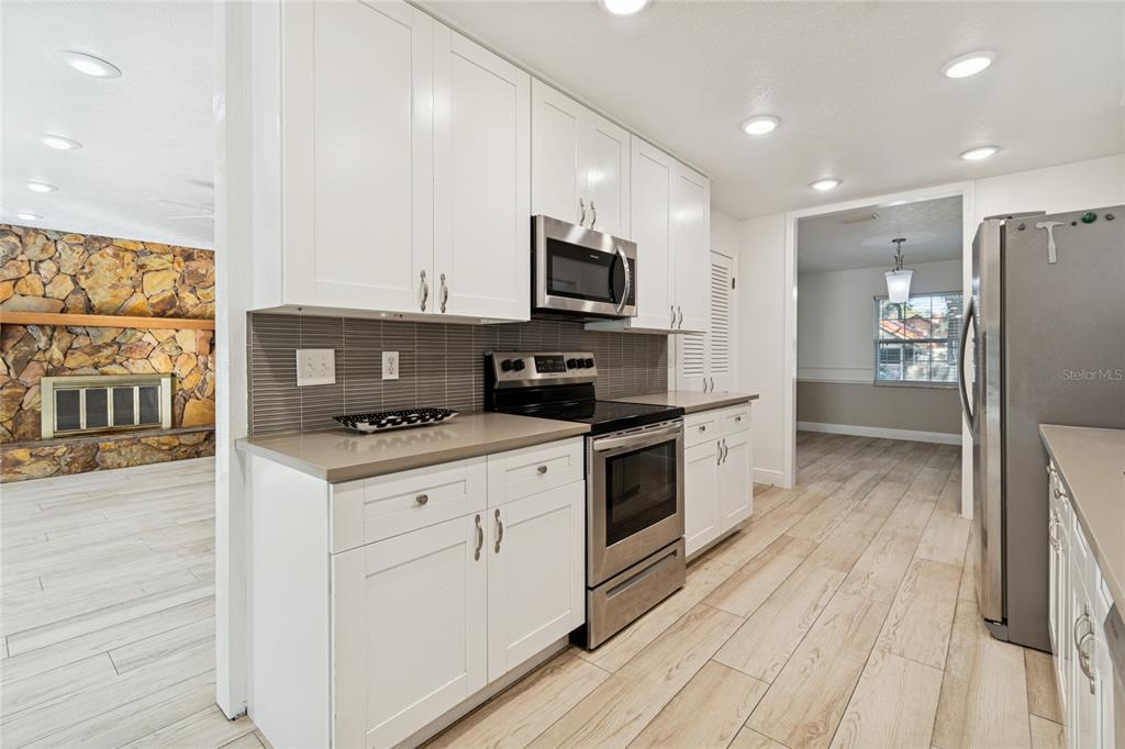 9628 Davis Road Tampa, FL 33637 - Photo 9 of 44 a kitchen with stainless steel appliances a stove top oven a sink a refrigerator white cabinets and wooden floor