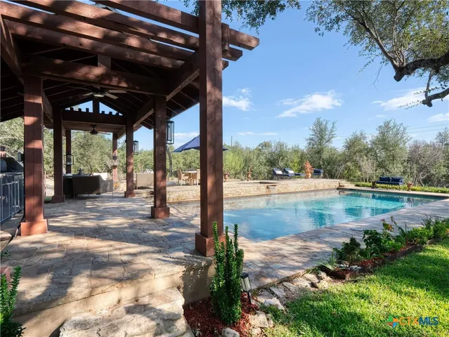 a view of swimming pool with lawn chairs under an umbrella
