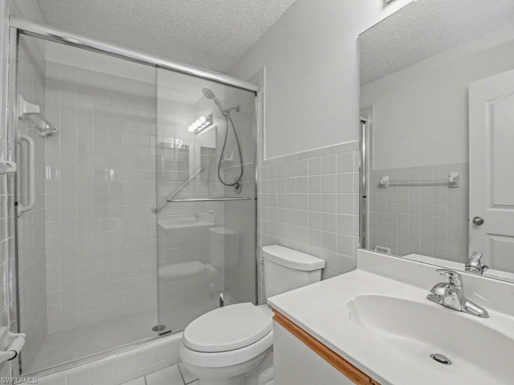565 Augusta Boulevard, Unit 10 Naples, FL 34113 - Photo 12 of 16 a bathroom with a sink a toilet and shower