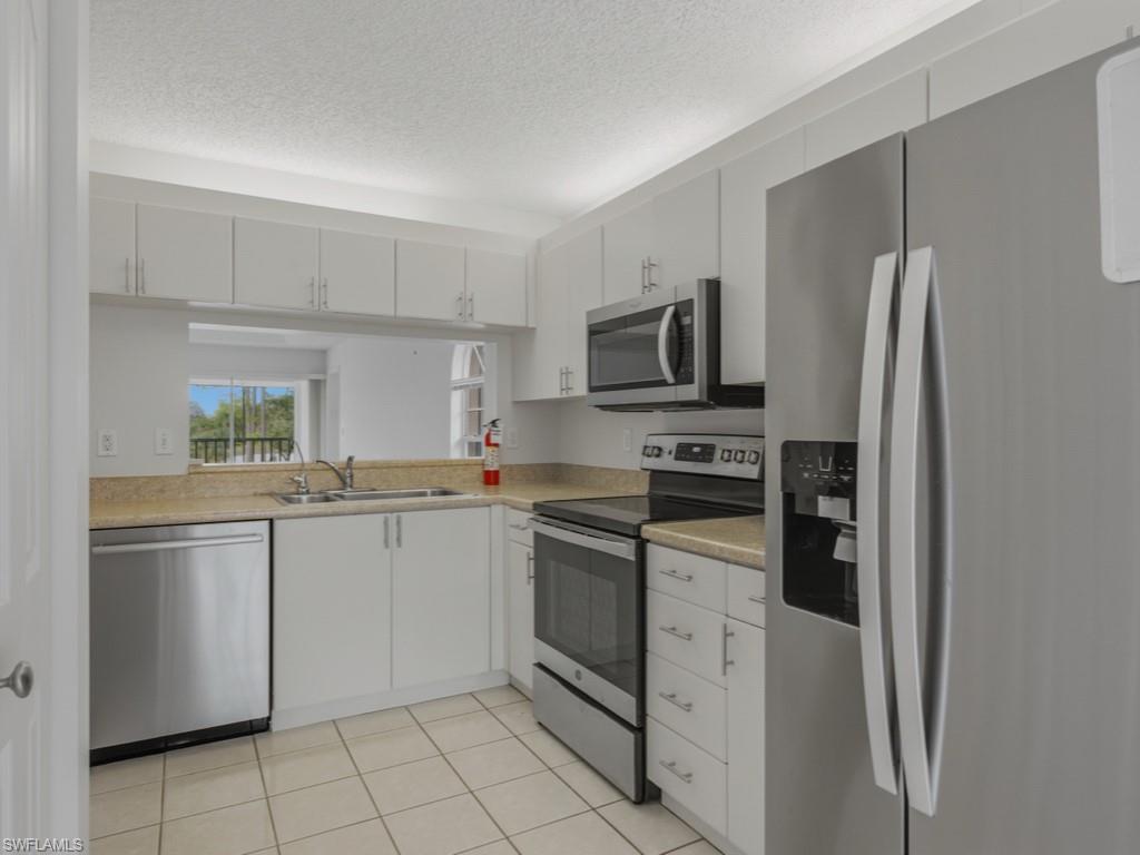 565 Augusta Boulevard, Unit 10 Naples, FL 34113 - Photo 4 of 16 a kitchen with white cabinets stainless steel appliances and a sink