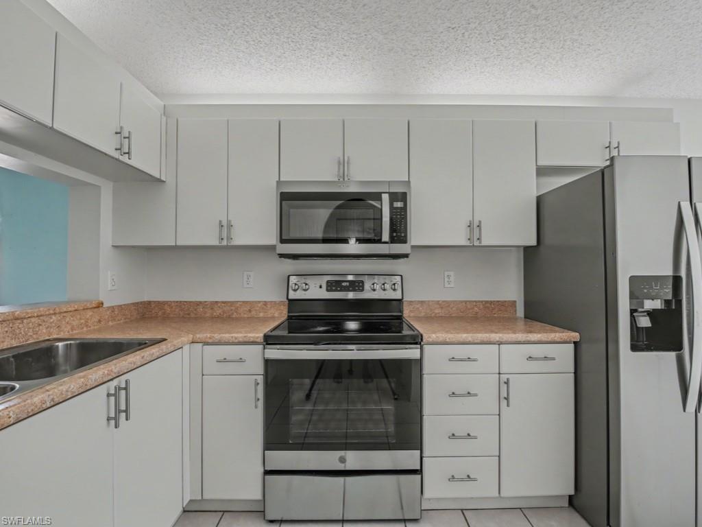 565 Augusta Boulevard, Unit 10 Naples, FL 34113 - Photo 5 of 16 a kitchen with white cabinets and stainless steel appliances