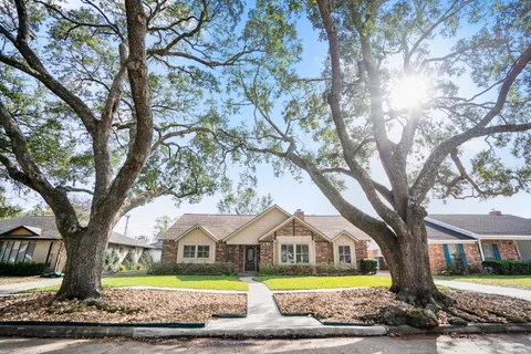 a view of house with a big yard and large trees