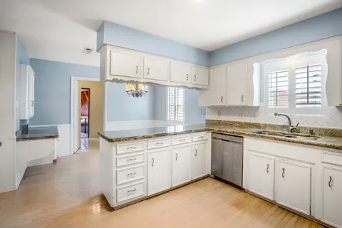 a kitchen with granite countertop a sink stove and cabinets