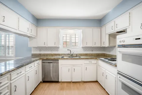 a white kitchen with granite countertop white cabinets and white appliances