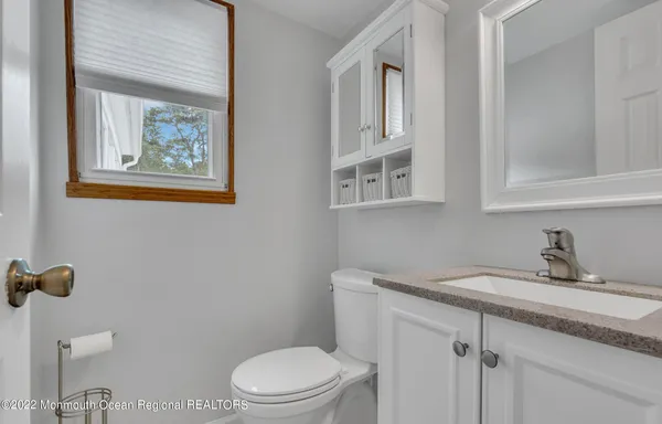 a bathroom with a granite countertop sink mirror vanity and toilet
