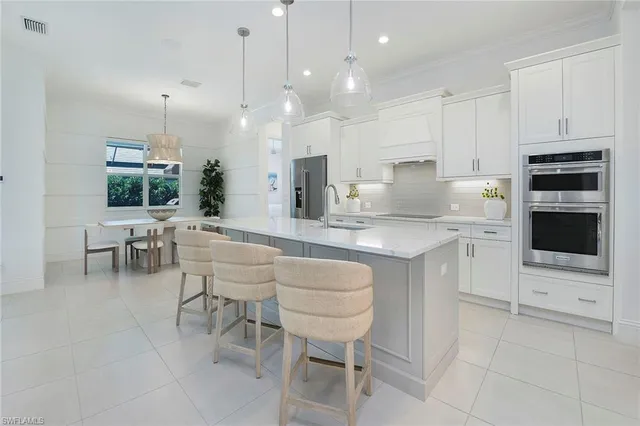 a kitchen with kitchen island a dining table chairs and a oven