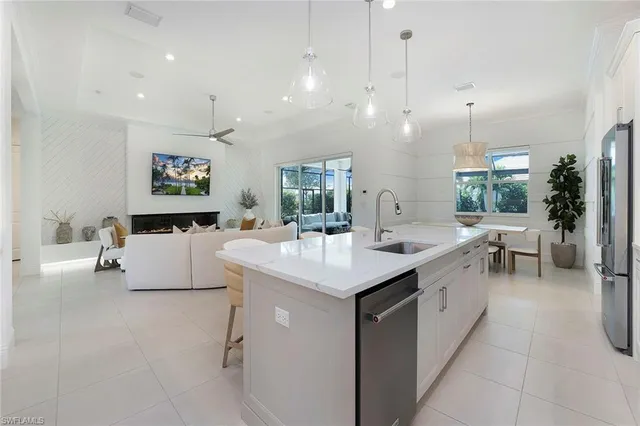 a large white kitchen with a large island oven a stove a sink with a dining table and chairs