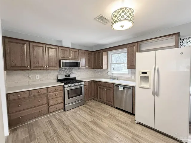a kitchen with stainless steel appliances granite countertop a refrigerator and a stove top oven