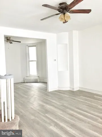 a view of a livingroom with wooden floor and a ceiling fan