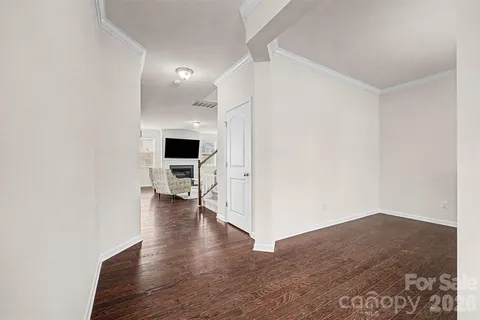 a view of a hallway with wooden floor and a bathroom