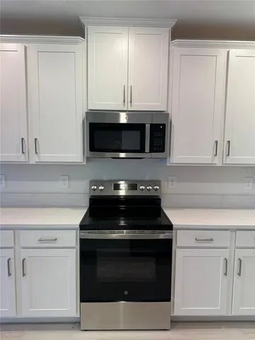 a kitchen with white cabinets and black appliances