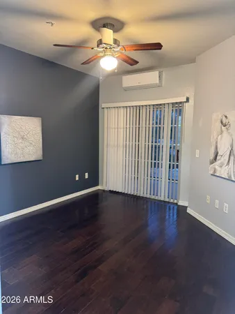 a view of an empty room with wooden floor and a ceiling fan