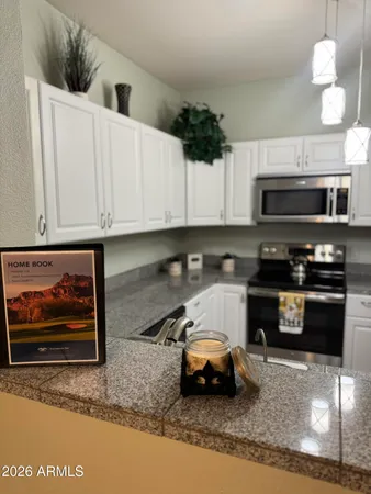 a kitchen with granite countertop a stove a microwave a sink and cabinets
