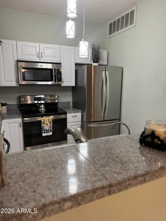 a kitchen with stainless steel appliances granite countertop a sink a stove a microwave and a refrigerator