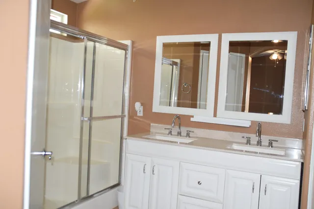 a bathroom with a double vanity sink mirror and shower
