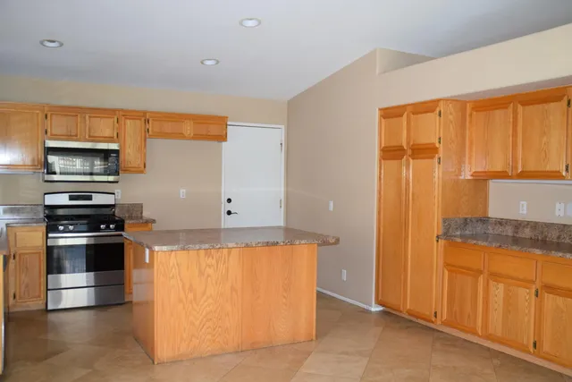 a kitchen with granite countertop a refrigerator and a stove top oven