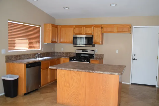 a kitchen with stainless steel appliances granite countertop a sink a stove a microwave a counter top and a refrigerator