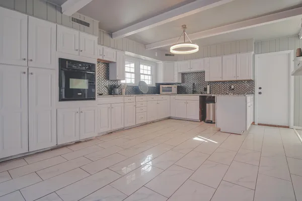 a kitchen with white cabinets and refrigerator