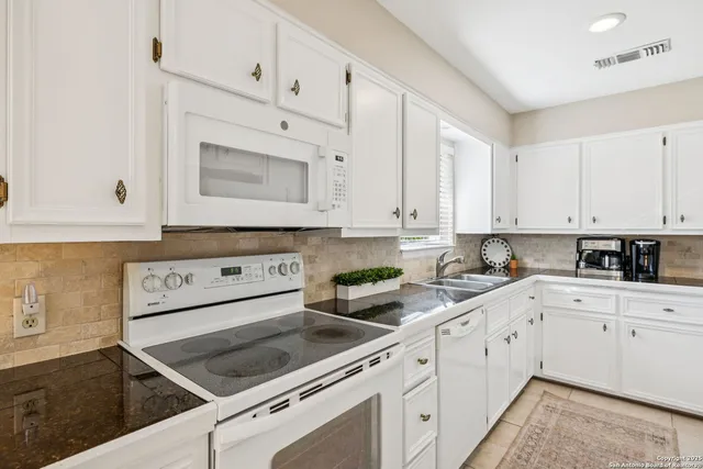 a kitchen with white cabinets and white appliances