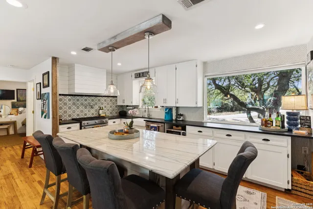 a kitchen with stainless steel appliances granite countertop a dining table chairs refrigerator sink and cabinets
