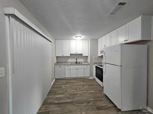 a kitchen with white cabinets and white appliances