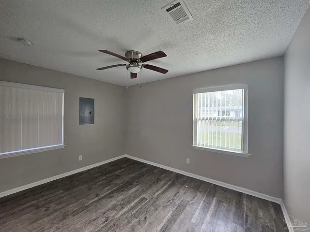 an empty room with wooden floor and windows