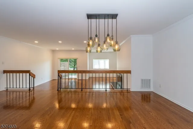 a view of an empty room with wooden floor and a kitchen