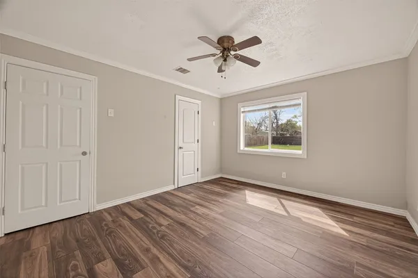 a view of empty room with wooden floor and fan